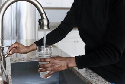 a lady pouring a glass of water from the tap