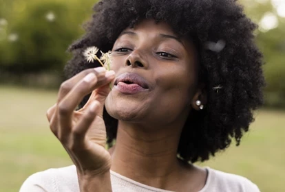 a lady blowing a dandelion