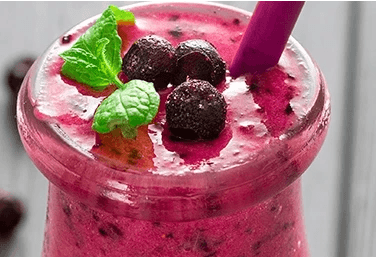 a glass of mixed berry smoothie and straw