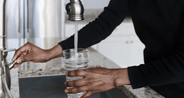 a lady pouring a glass of water from the tap