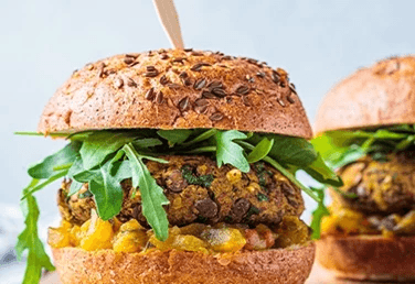 two spicy bean burgers in buns with salad and salsa