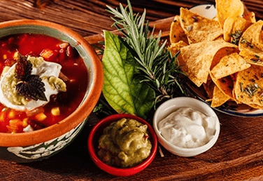 a mexican bean soup board with nachos and toppings