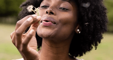 a lady blowing a dandelion