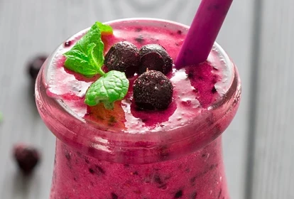 a glass of mixed berry smoothie and straw