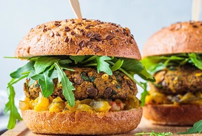 two spicy bean burgers in buns with salad and salsa